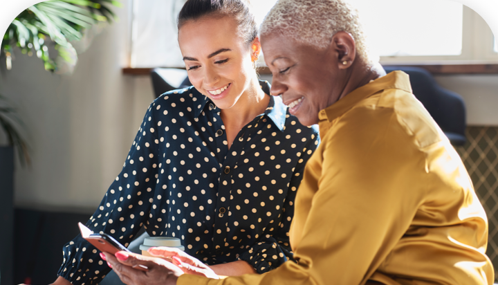 Image of two women sitting together and looking at a smartphone